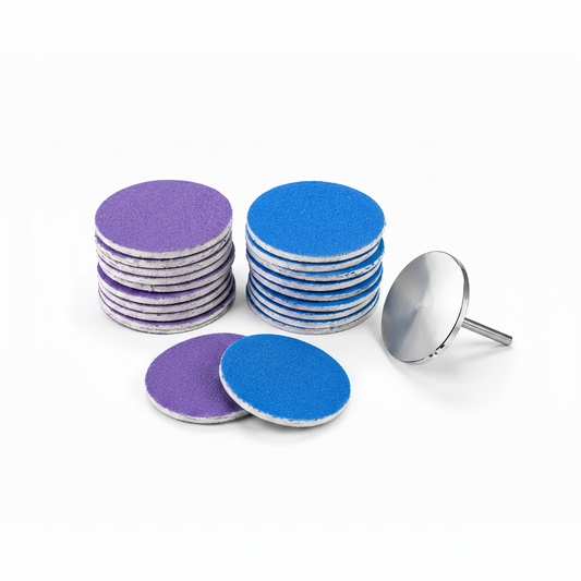 Set disc si 40 de rezerve abrazive autoadezive pentru pedichiura Pododisc, cu diametrul de 25mm, dispuse in doua stive colorate in mov si albastru, langa un disc suport metalic.