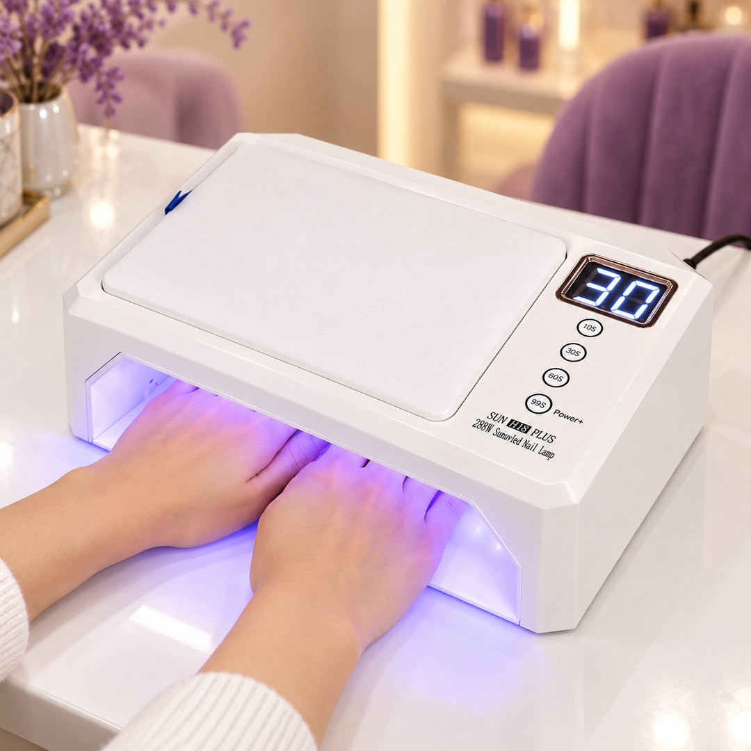Lampă UV LED SUN H18 PLUS în funcțiune pe masa de manichiură, cu ambele mâini poziționate în deschiderea frontală, lumină violetă în interior și suport alb pentru mână deasupra.