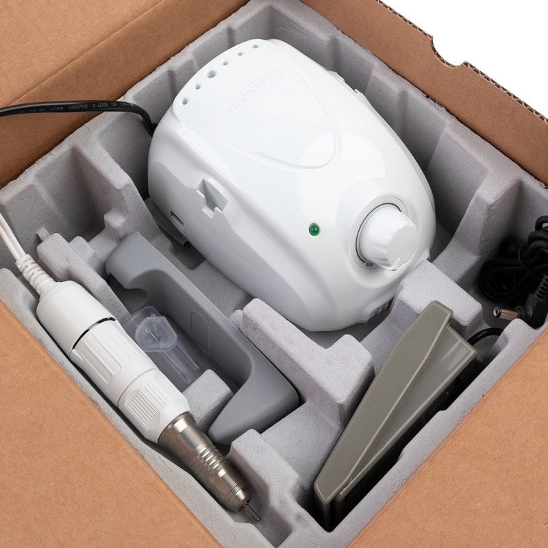Unitatea centrala alba, mandrina si accesoriile frezei electrice Marathon ambalate in siguranta in compartimentele din carton ale cutiei originale de livrare.