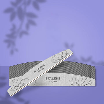 Set de 25 de pile semilună STALEKS EXPERT 40, granulație 100/100, cu abraziv alb și desen floral, prezentat pe fundal mov cu o pilă oblică în prim-plan.